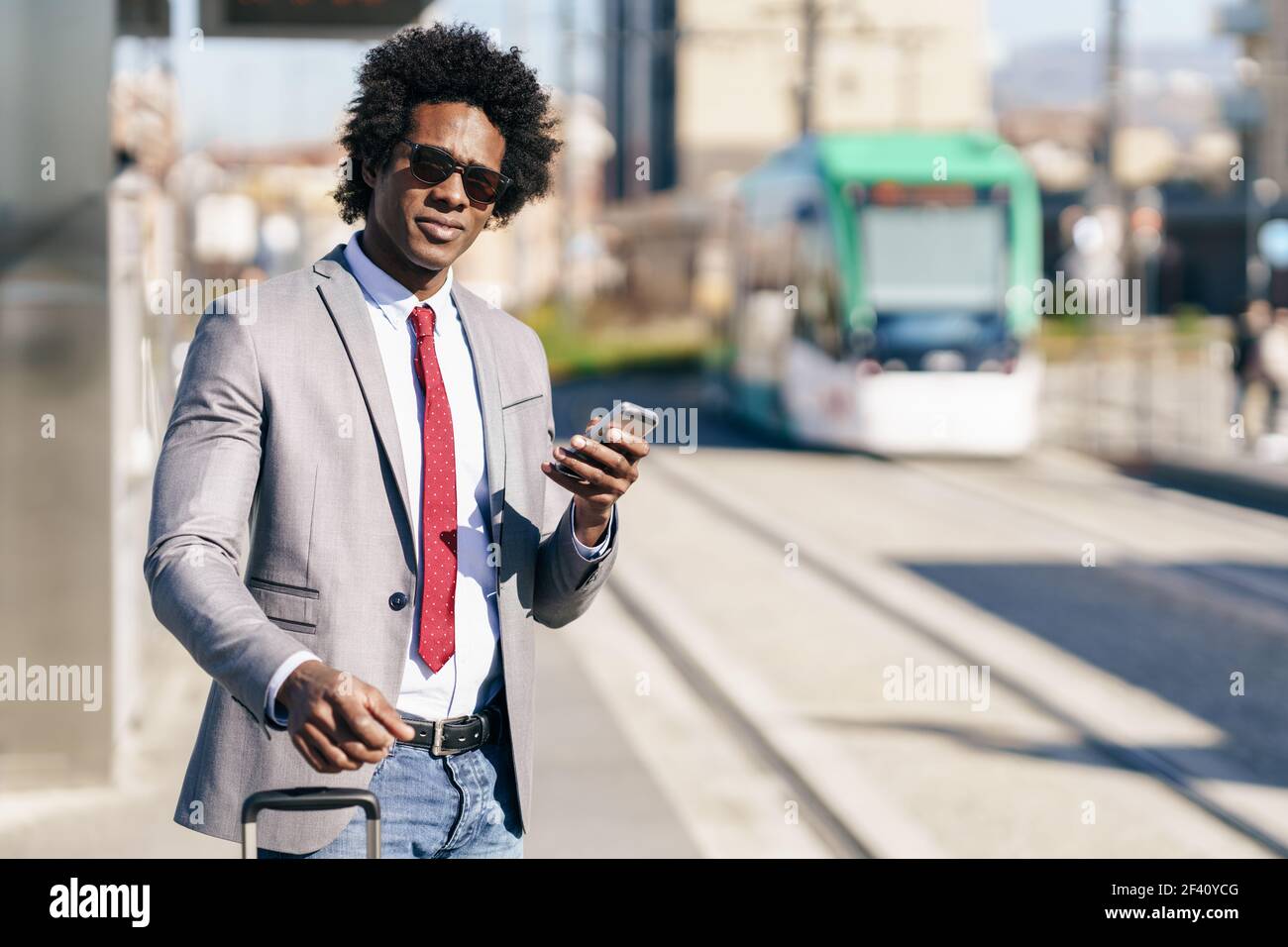 Homme d'affaires noir attendant le prochain train. Homme avec des cheveux afro navettage.. Homme d'affaires noir attendant le prochain train Banque D'Images