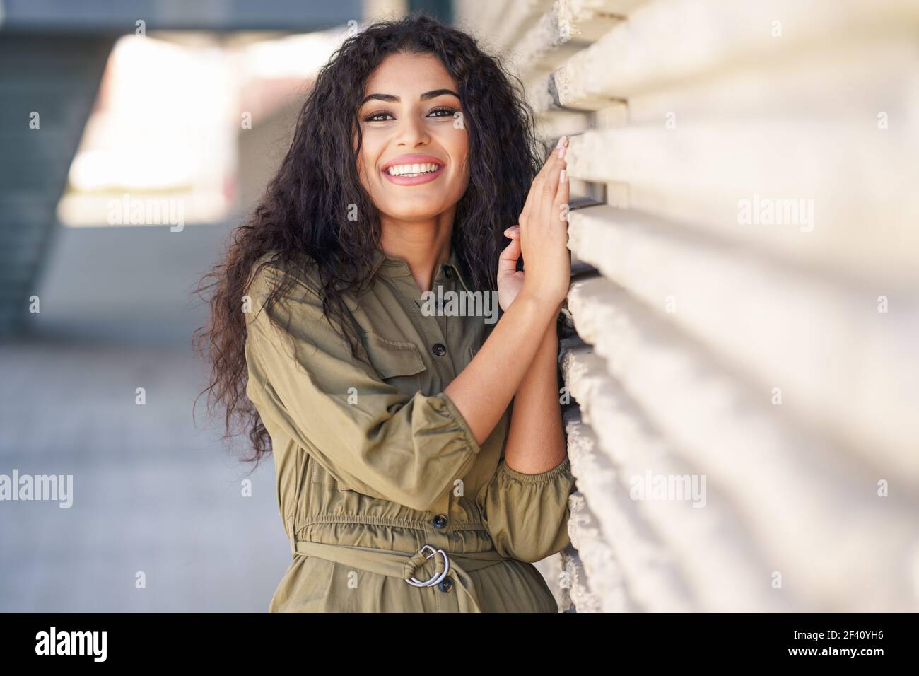 Bonne femme arabe aux cheveux bouclés dans un fond urbain. Jeune femme arabe avec des cheveux bouclés à l'extérieur Banque D'Images