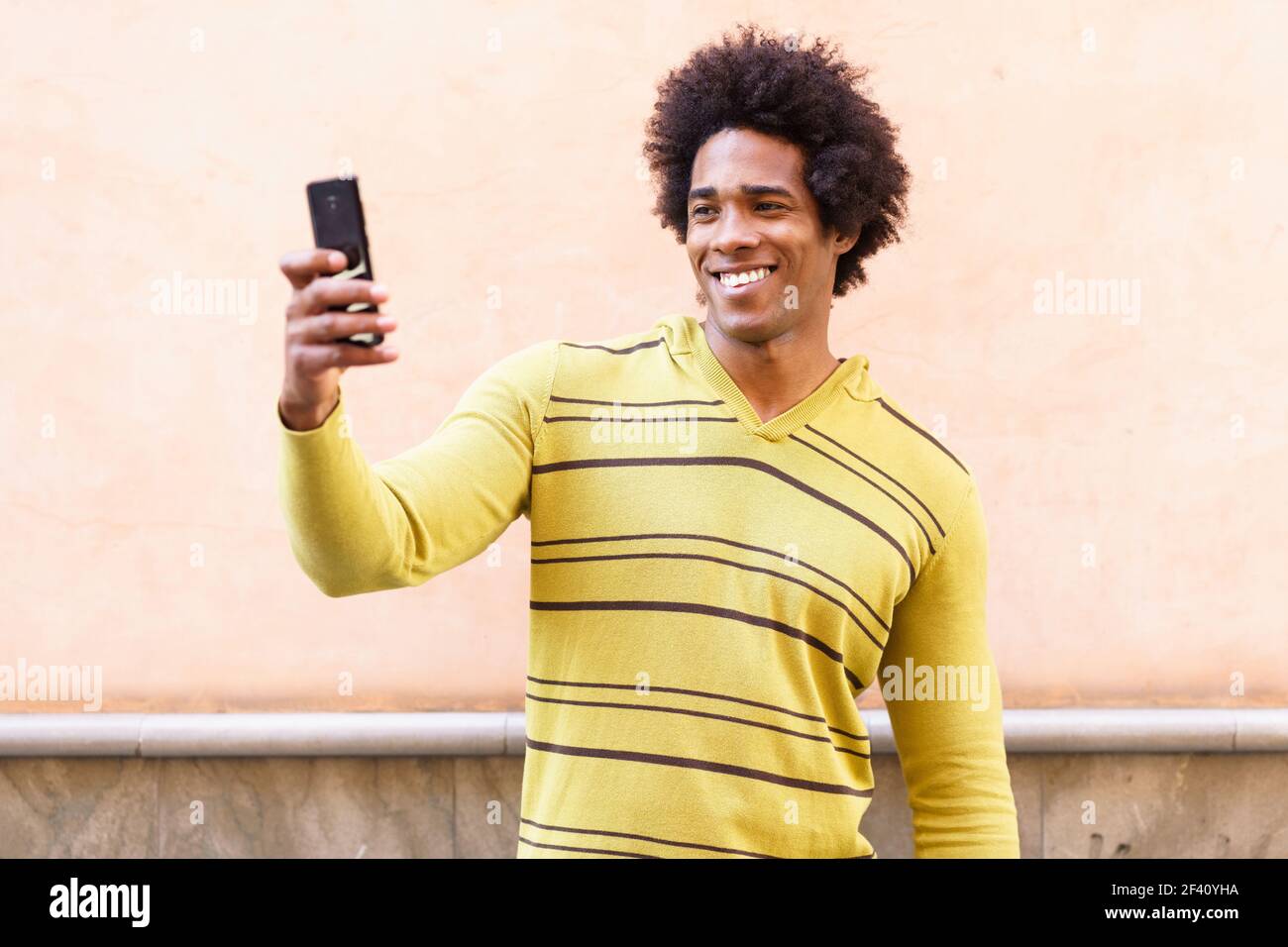 Homme noir avec cheveux afro et casque à l'aide d'un smartphone pour prendre des photos. Homme noir avec cheveux afro et casque à l'aide d'un smartphone. Banque D'Images