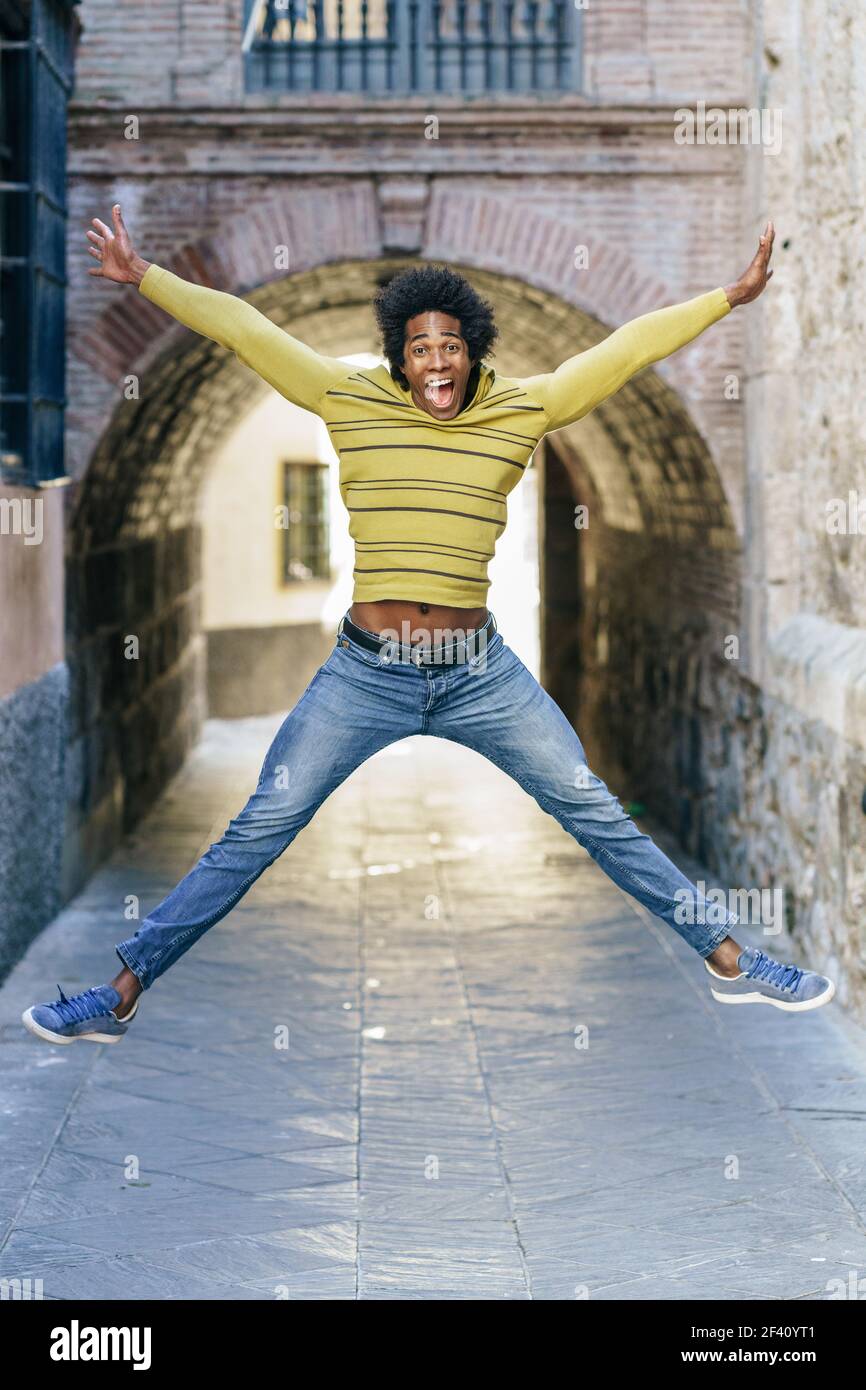 Homme noir avec des cheveux afro sautant pour la joie dans la rue. Homme noir avec saut de cheveux afro pour la joie Banque D'Images
