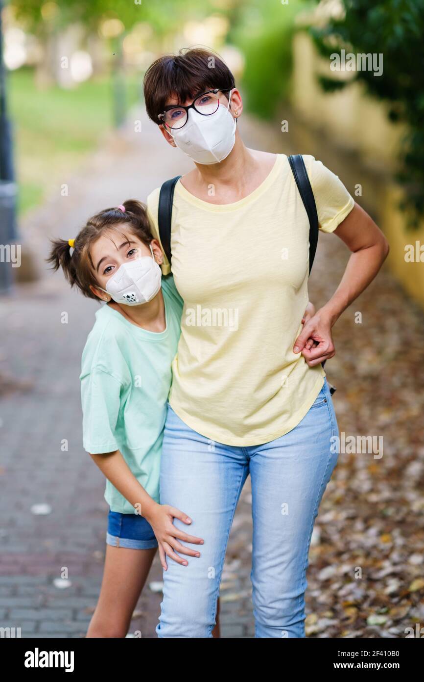 Mère et fille d'âge moyen debout dans la rue et portant des masques en raison de la pandémie Covid-19. Mère et fille d'âge moyen debout dans la rue et portant des masques Banque D'Images