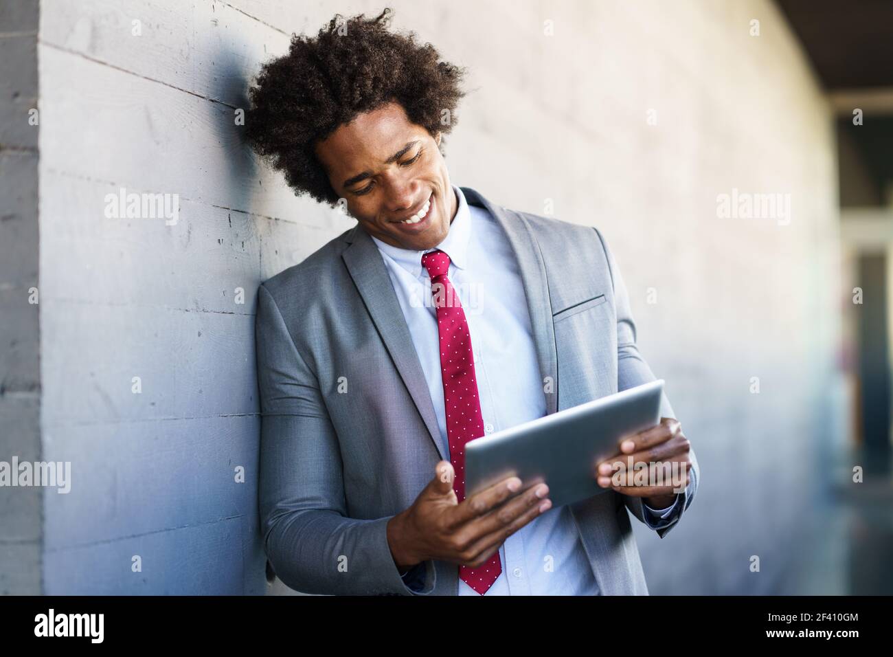 Homme d'affaires noir utilisant une tablette numérique en milieu urbain. Homme avec cheveux afro.. Homme d'affaires noir utilisant une tablette numérique en milieu urbain Banque D'Images