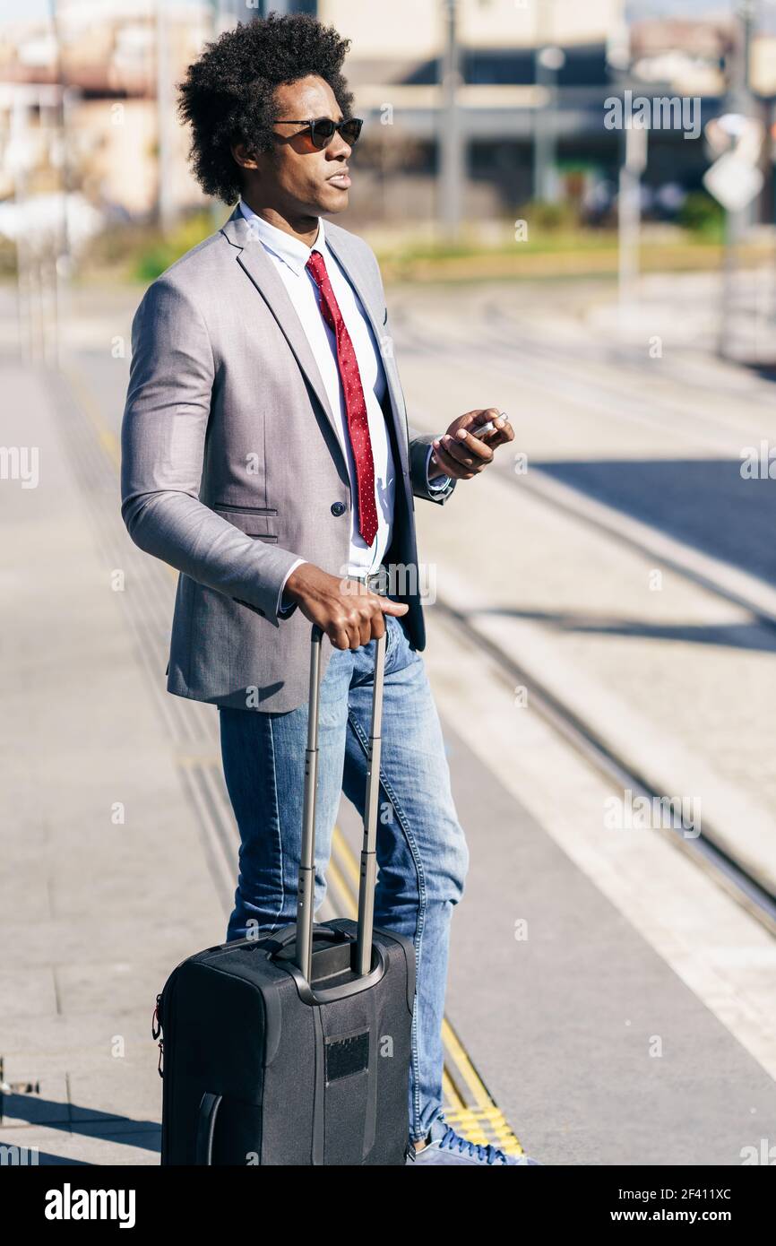 Homme d'affaires noir attendant le prochain train. Homme avec des cheveux afro navettage.. Homme d'affaires noir attendant le prochain train Banque D'Images