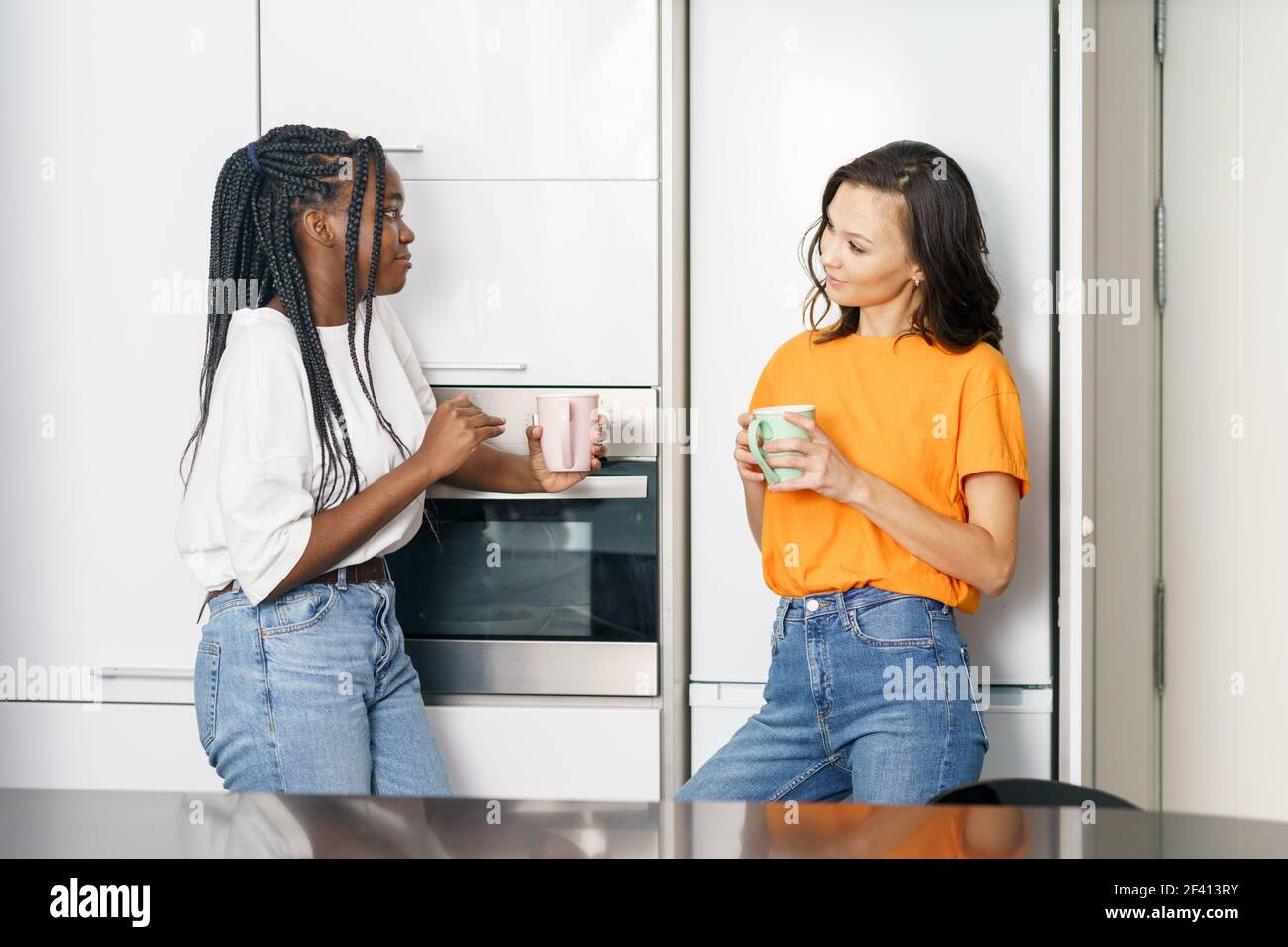Deux étudiants amis prenant une pause-café ensemble à la maison multiethnique femmes. Deux amis étudiants prenant une pause-café ensemble à la maison. Banque D'Images