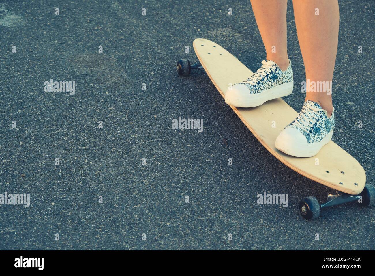 Les jambes des jeunes filles debout sur le long-board de près et beaucoup d'espace d'imitation. Les jambes des filles debout sur le long-board de près et beaucoup d'espace de copie Banque D'Images