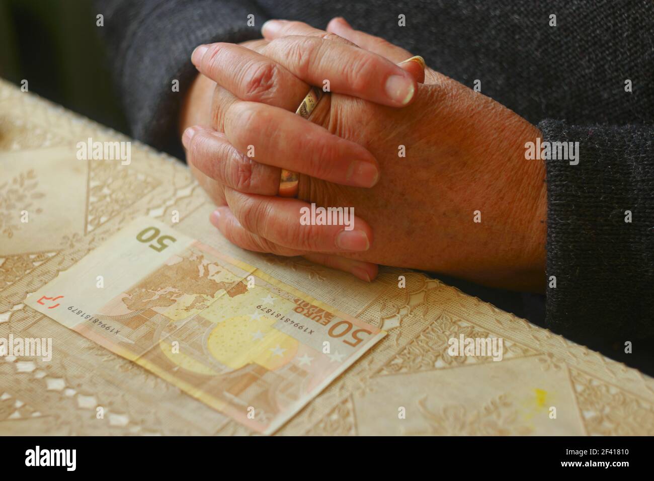 Mains de la femme âgée et note de 50 euros sur la table devant elle Banque D'Images