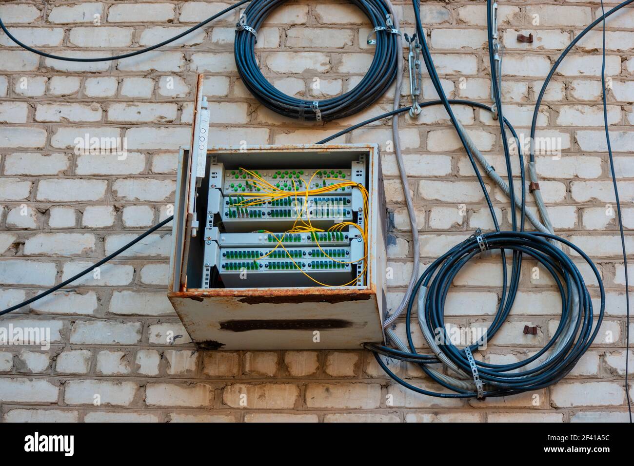 Panneau de raccordement à fibre optique sur le mur de l'immeuble d'appartements avec bobines de fils à proximité. Panneau de raccordement à fibre optique sur le mur de l'immeuble d'appartements Banque D'Images