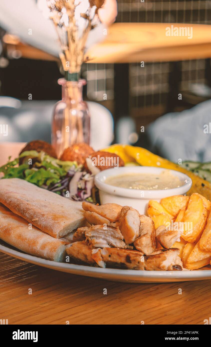 Boulettes de falafel servies avec du poulet grillé et des légumes sur une table de café. Boulettes de falafel servies avec du poulet grillé et des légumes Banque D'Images