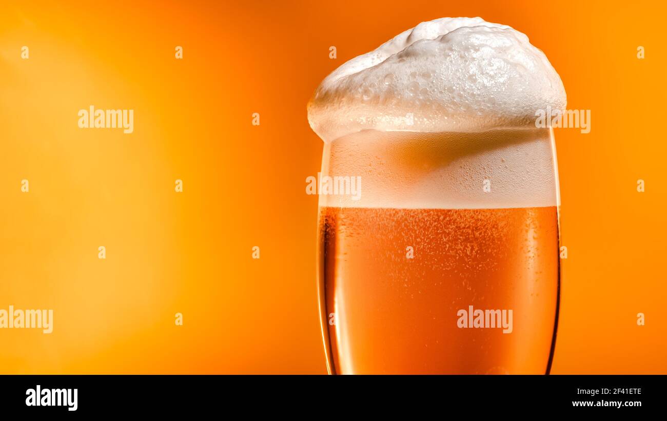 La bière lager s'installe dans le verre avec un bouchon blanc en mousse Banque D'Images