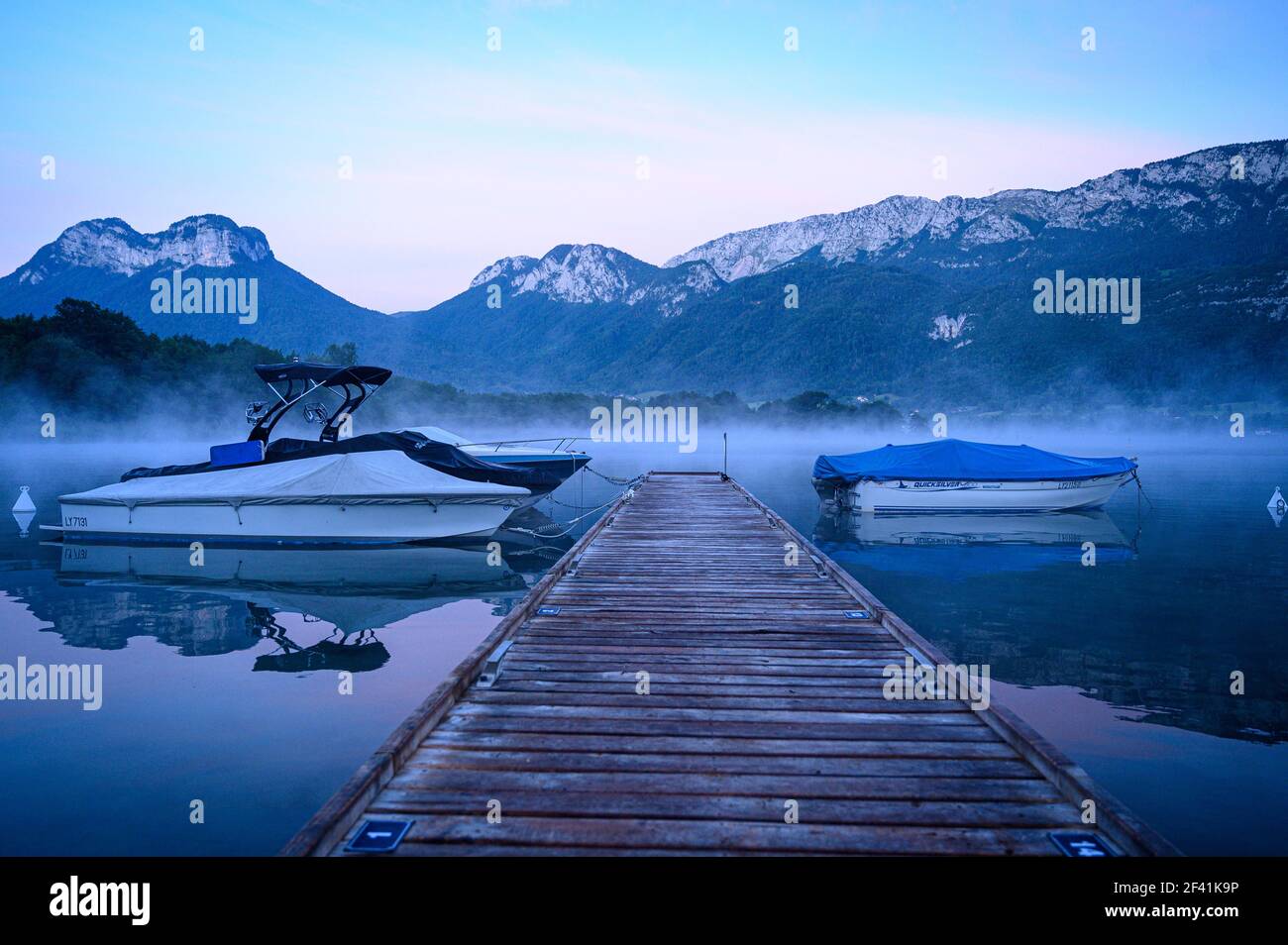 Jetée en bois vide avec bateaux à moteur sur un lac de montagne calme Le matin (lac d'Annecy) Banque D'Images