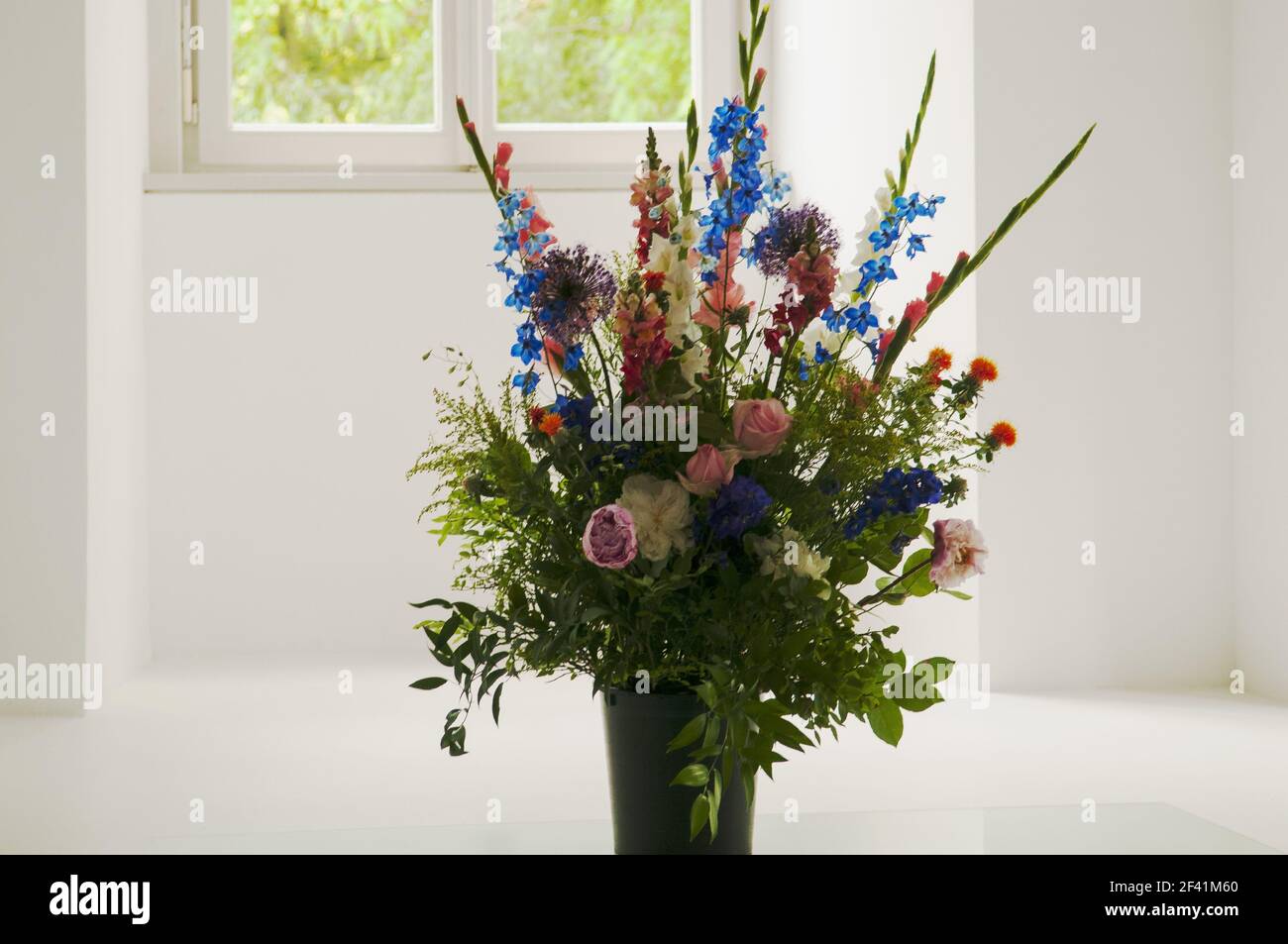 Des fleurs multicolores dans un vase en verre décorent une pièce vide. Banque D'Images