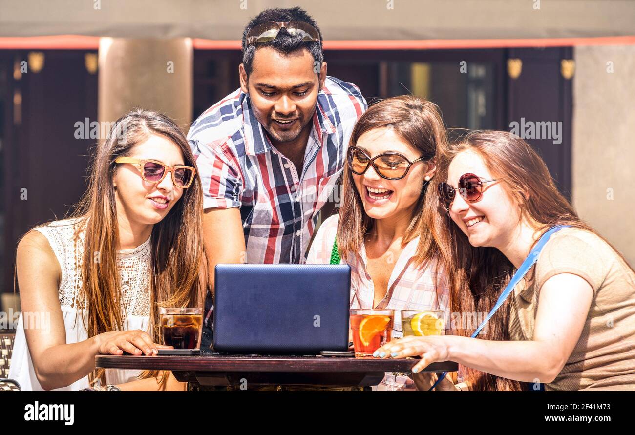 Amis multiraciaux au bar à cocktails s'amuser avec un ordinateur portable - Communauté connectée de jeunes étudiants utilisant un pc sur les réseaux sociaux réseaux multimédias Banque D'Images