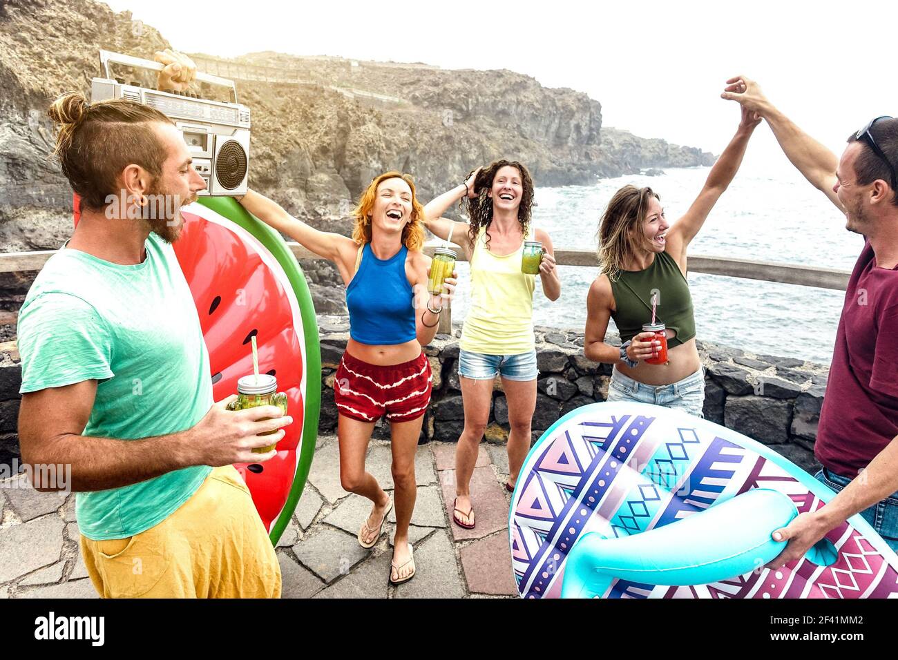 Les jeunes amis vacanciers s'amusent à la piscine naturelle en voyage Emplacement - des millenial heureux dansant et buvant des cocktails à autre plage Banque D'Images