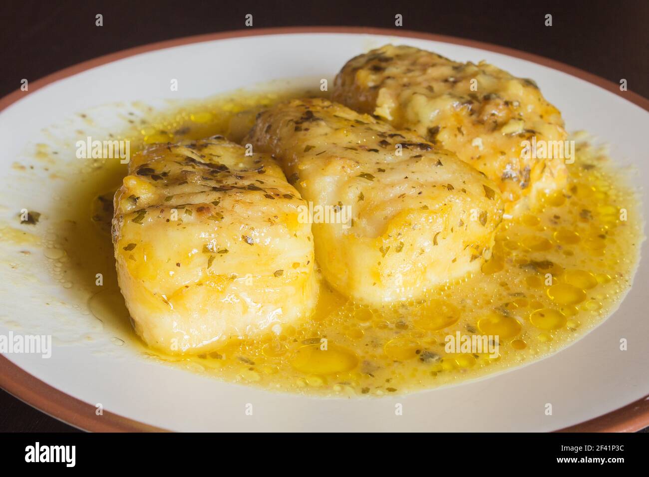 Présentation de trois délicieux moules à merlu dans une sauce verte sur une assiette blanche. Poisson et nourriture saine. Banque D'Images