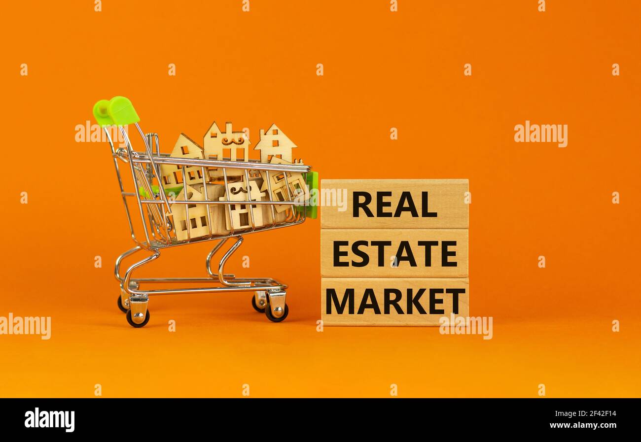 Symbole du marché immobilier. Blocs en bois, mots "marché immobilier" sur fond orange magnifique. Chariot avec maisons miniatures en bois. Bus Banque D'Images