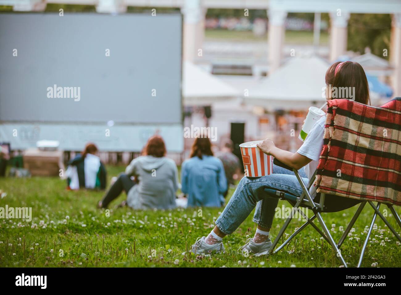 femme assise dans une chaise de camping et regardant un film au cinéma en plein air. manger du pop-corn et boire du soda Banque D'Images