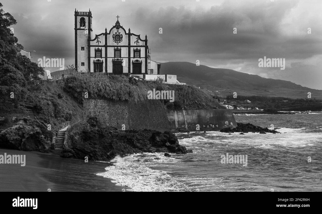 Une photo en niveaux de gris d'une église azorienne et de la plage De San Roque près de Ponta Delgada Banque D'Images