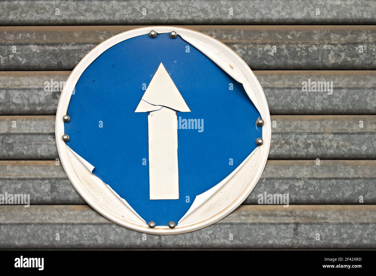 Un ancien panneau de signalisation avec une flèche qui se trouve sur un volet métallique Banque D'Images