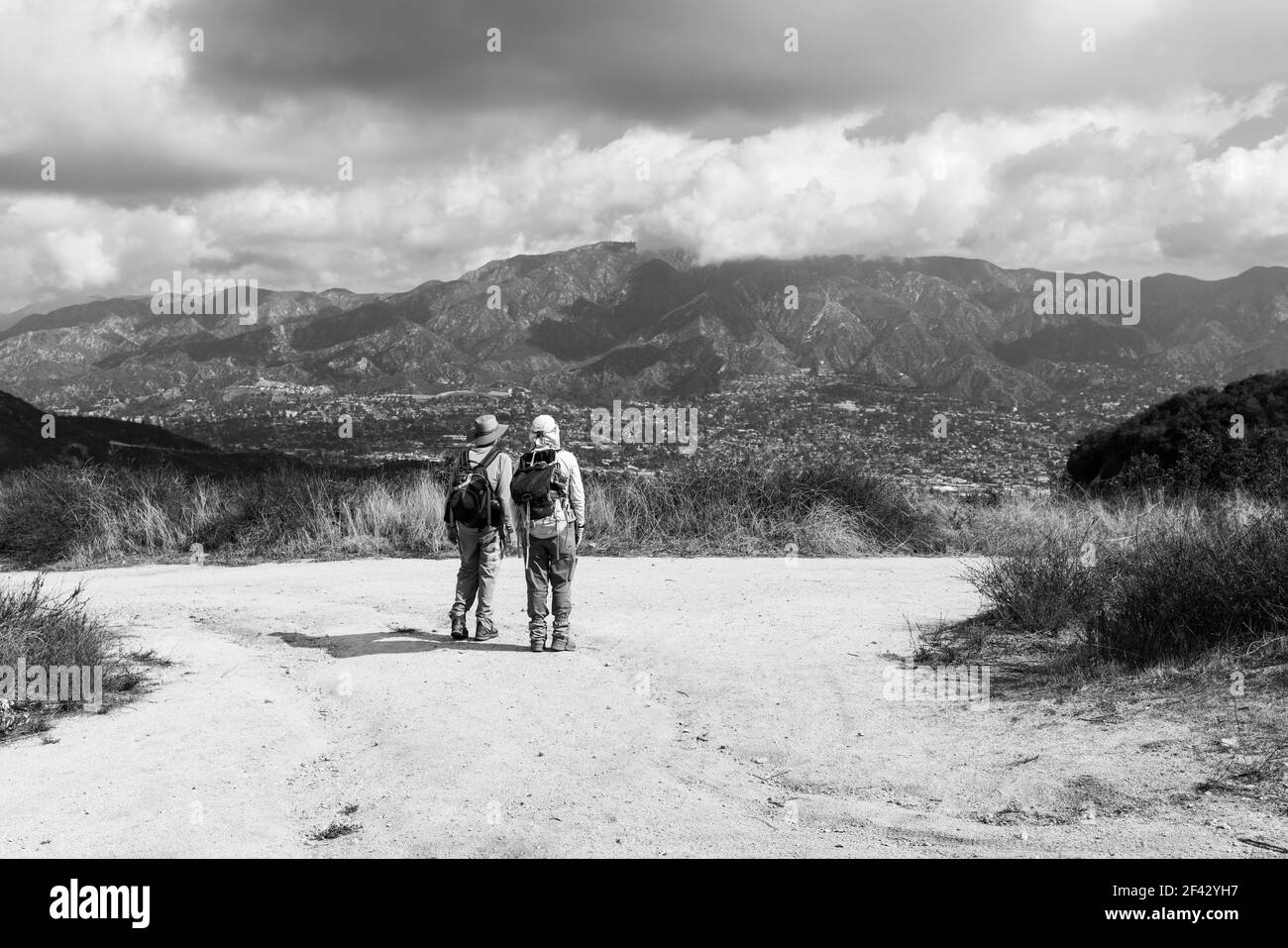 Vue en noir et blanc des randonneurs faisant une pause pour regarder la Crescenta et le Mont Lukens dans les montagnes San Gabriel du comté de Los Angeles, en Californie. Banque D'Images