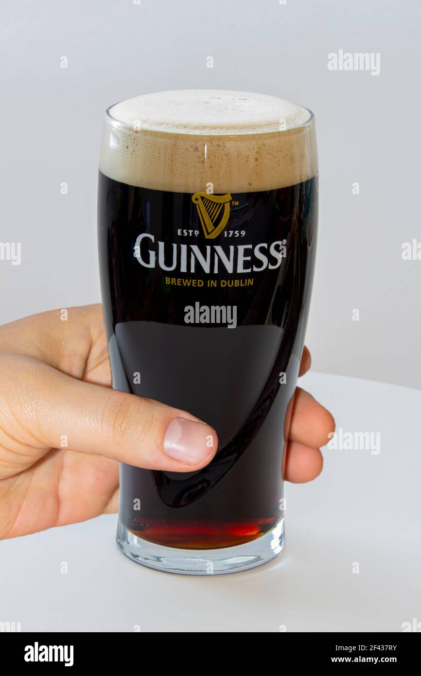 Calgary, Alberta, Canada. 12 mars 2021. Personne tenant une pinte de bière Guinness sur fond blanc Banque D'Images