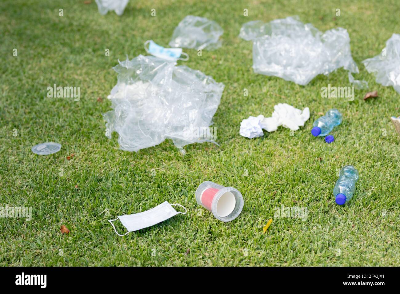 Des bouteilles en plastique, des déchets et un vieux masque facial reposant sur l'herbe dans un champ Banque D'Images