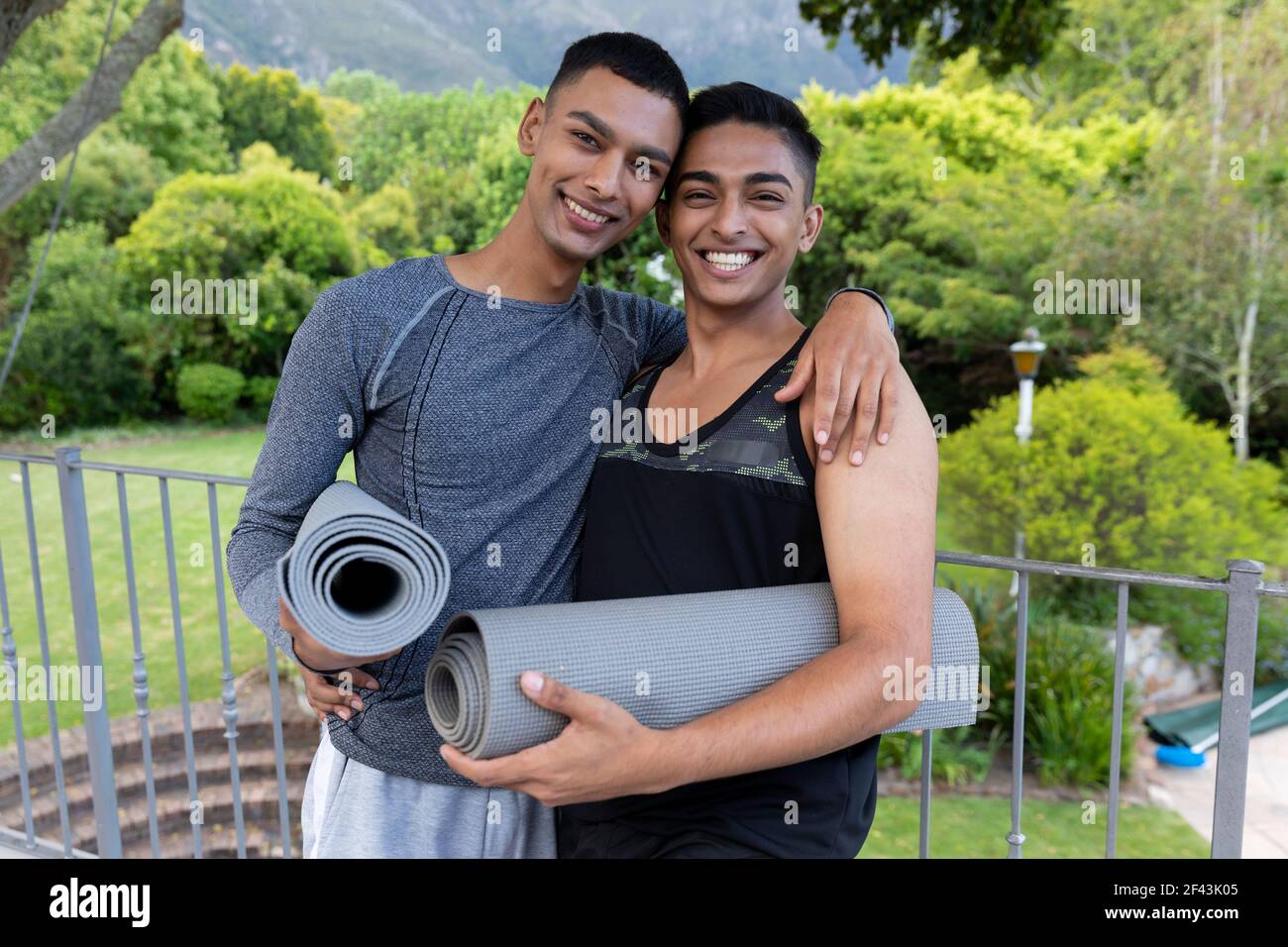 Portrait de divers couples homosexuels hommes tenant des tapis de yoga et sourire sur le balcon Banque D'Images