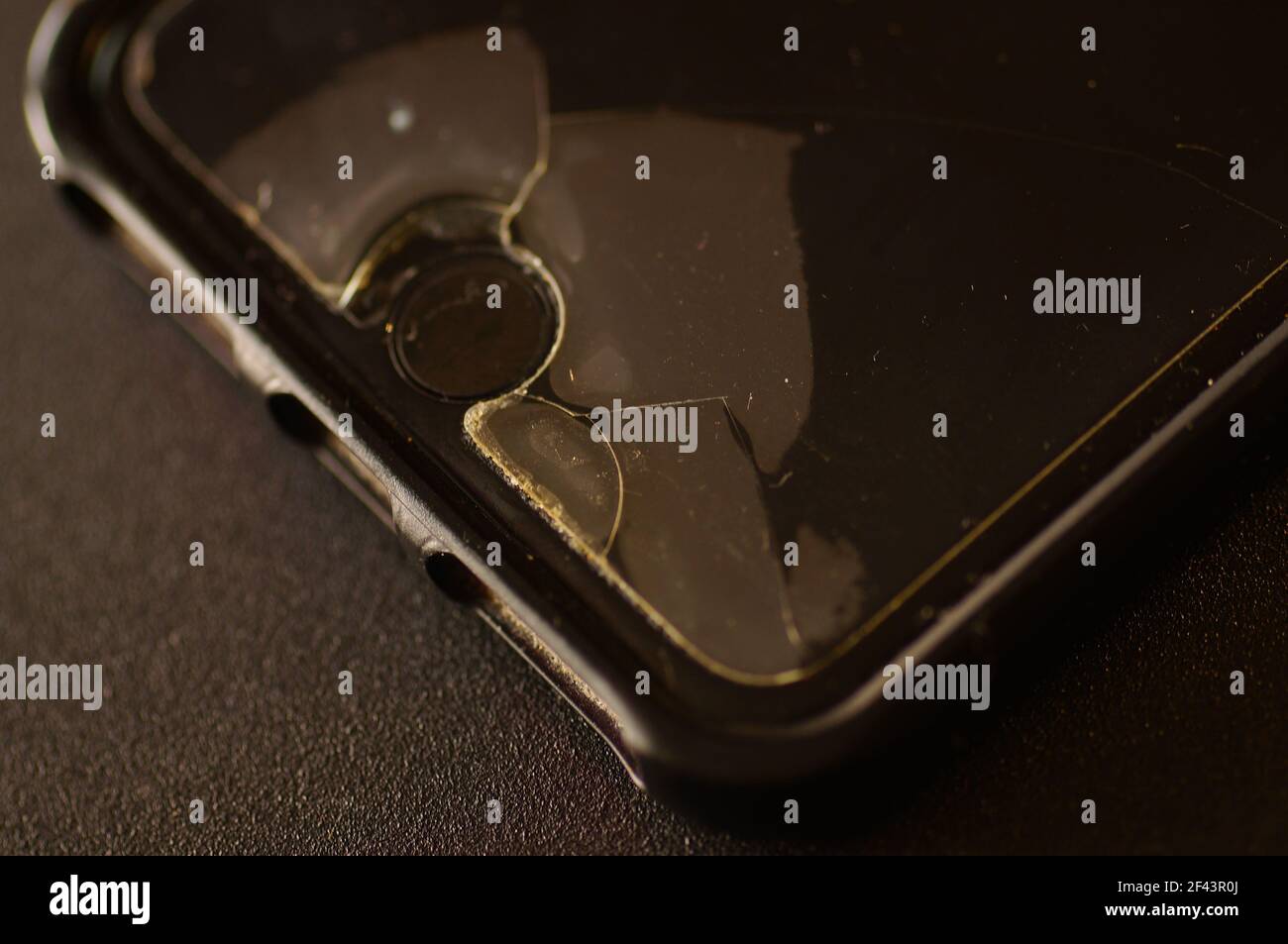 Vitre de protection du smartphone : endommagée, fissurée, usée. Ancienne protection de l'écran. Téléphone sale, noir, usé. Banque D'Images