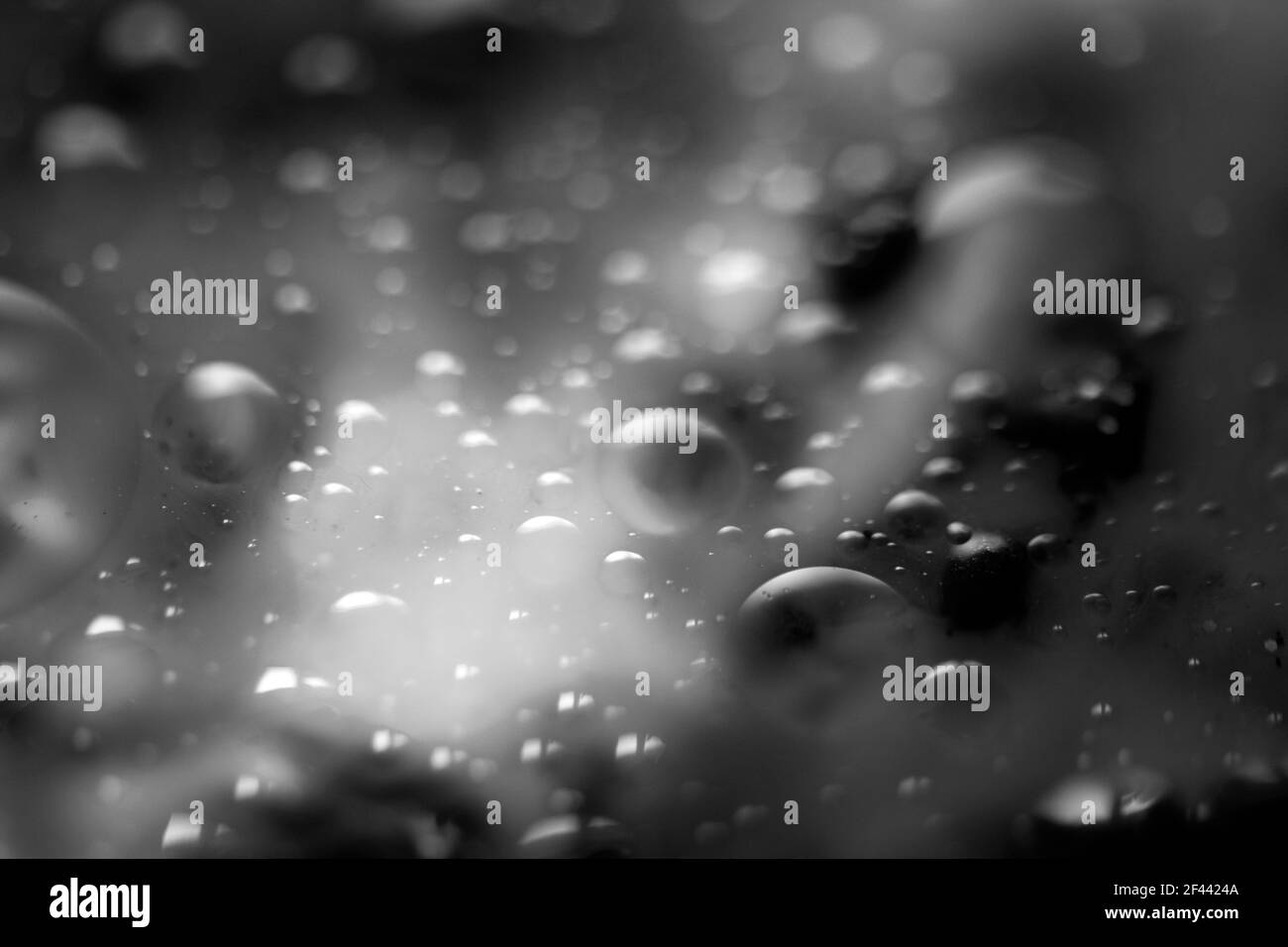 Arrière-plan abstrait noir et blanc, des bulles s'élevant dans une substance liquide. Arrière-plan flou Banque D'Images