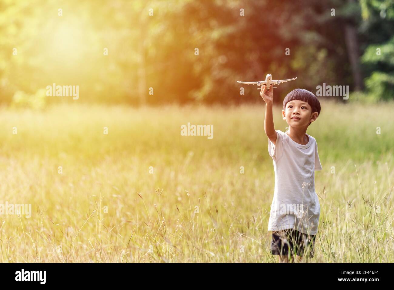 Mignon enfant asiatique jouant un avion dans le parc en plein air Happy Asian garçon tenant un avion court dans un pré avec le coucher du soleil. Banque D'Images