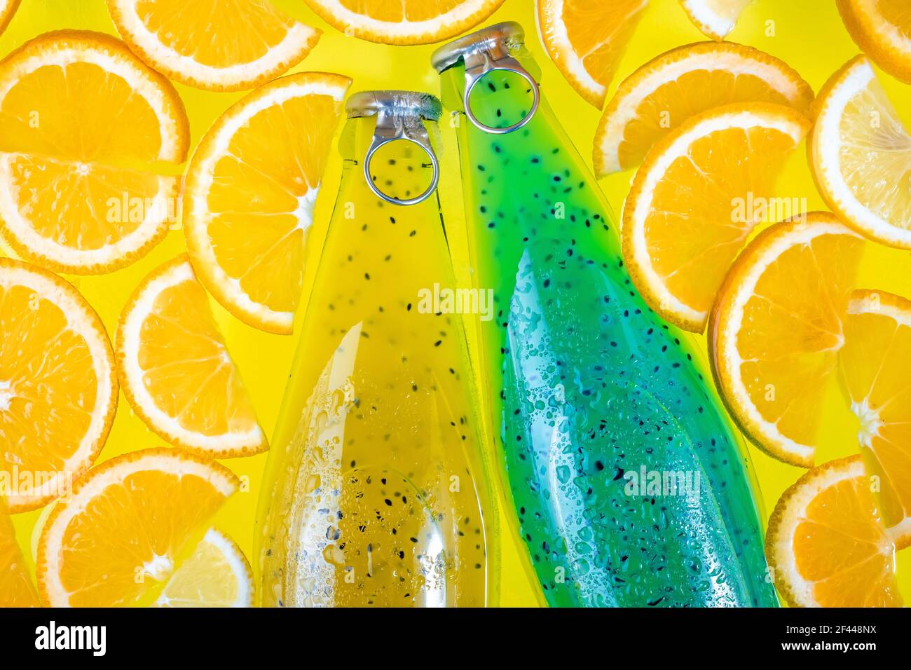 Boisson végétalienne saine, boisson non alcoolisée, jus d'agrumes. Deux bouteilles en verre sur fond tropical jaune vif. Petit déjeuner d'été le matin. Smoothie aux fruits avec Banque D'Images
