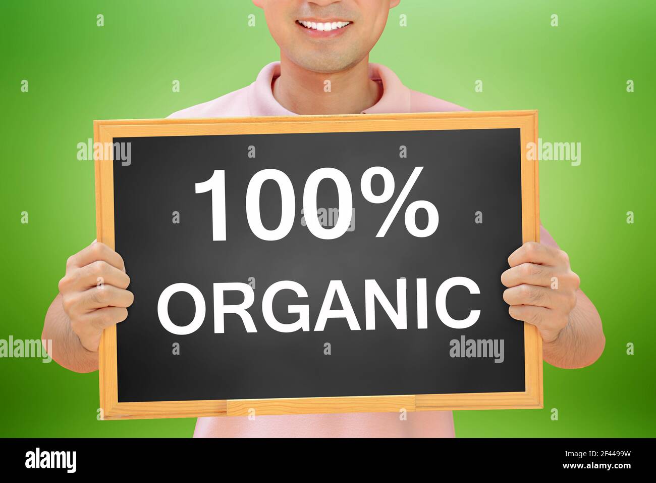 100% DE TEXTE ORGANIQUE sur le tableau noir tenu par l'homme souriant Banque D'Images