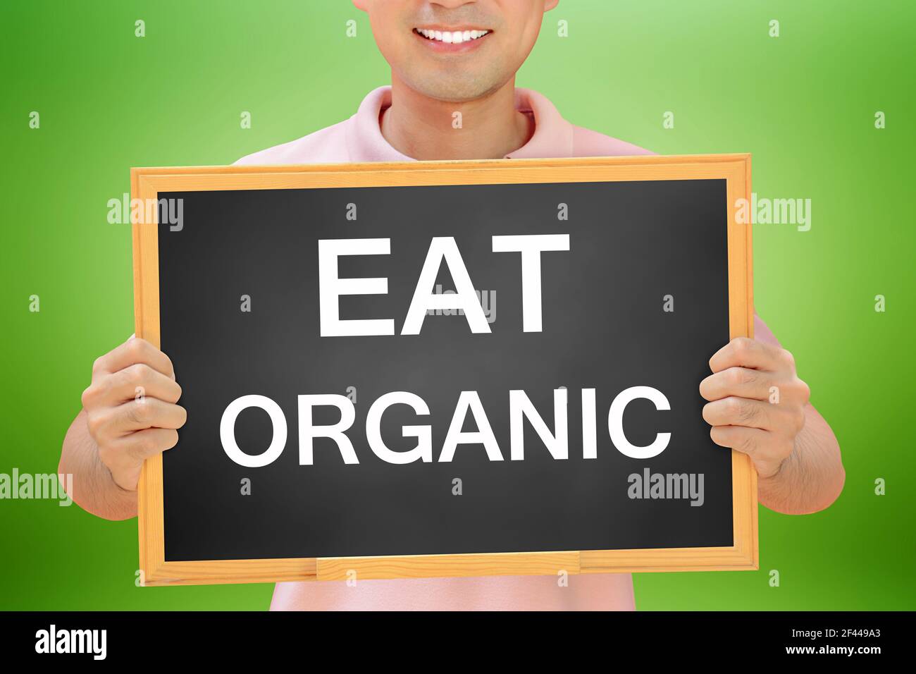 MANGEZ DU texte ORGANIQUE sur le tableau noir tenu par l'homme souriant Banque D'Images