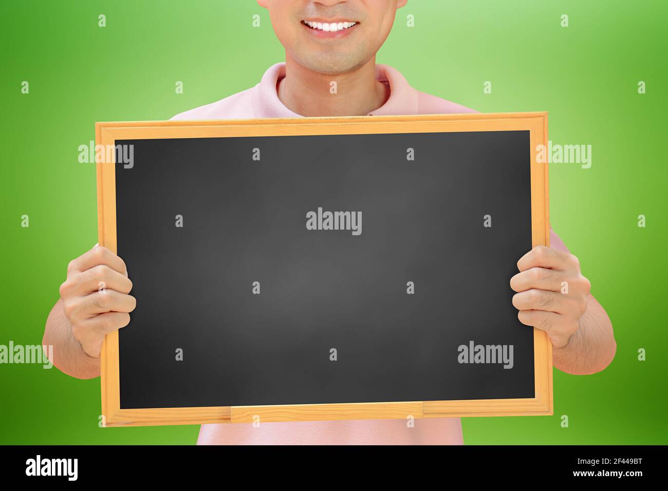 Homme souriant tenant un tableau noir vierge - peut remplir vos textes et être utilisé comme écriteau, avis et panneaux publicitaires, etc Banque D'Images