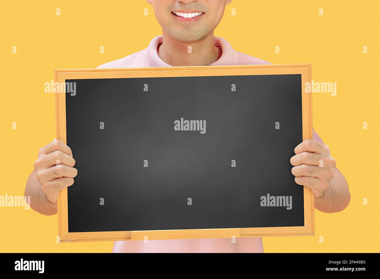 Homme souriant tenant un tableau noir vierge - peut remplir vos textes et être utilisé comme écriteau, avis et panneaux publicitaires, etc Banque D'Images