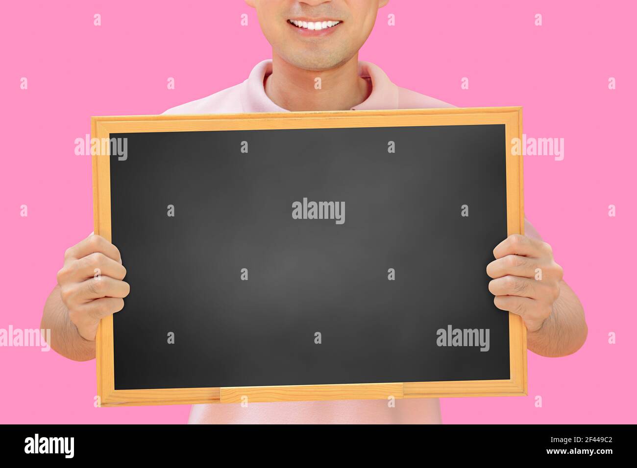 Homme souriant tenant un tableau noir vierge - peut remplir vos textes et être utilisé comme écriteau, avis et panneaux publicitaires, etc Banque D'Images