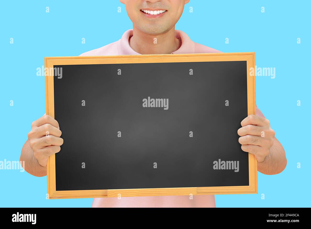 Homme souriant tenant un tableau noir vierge - peut remplir vos textes et être utilisé comme écriteau, avis et panneaux publicitaires, etc Banque D'Images