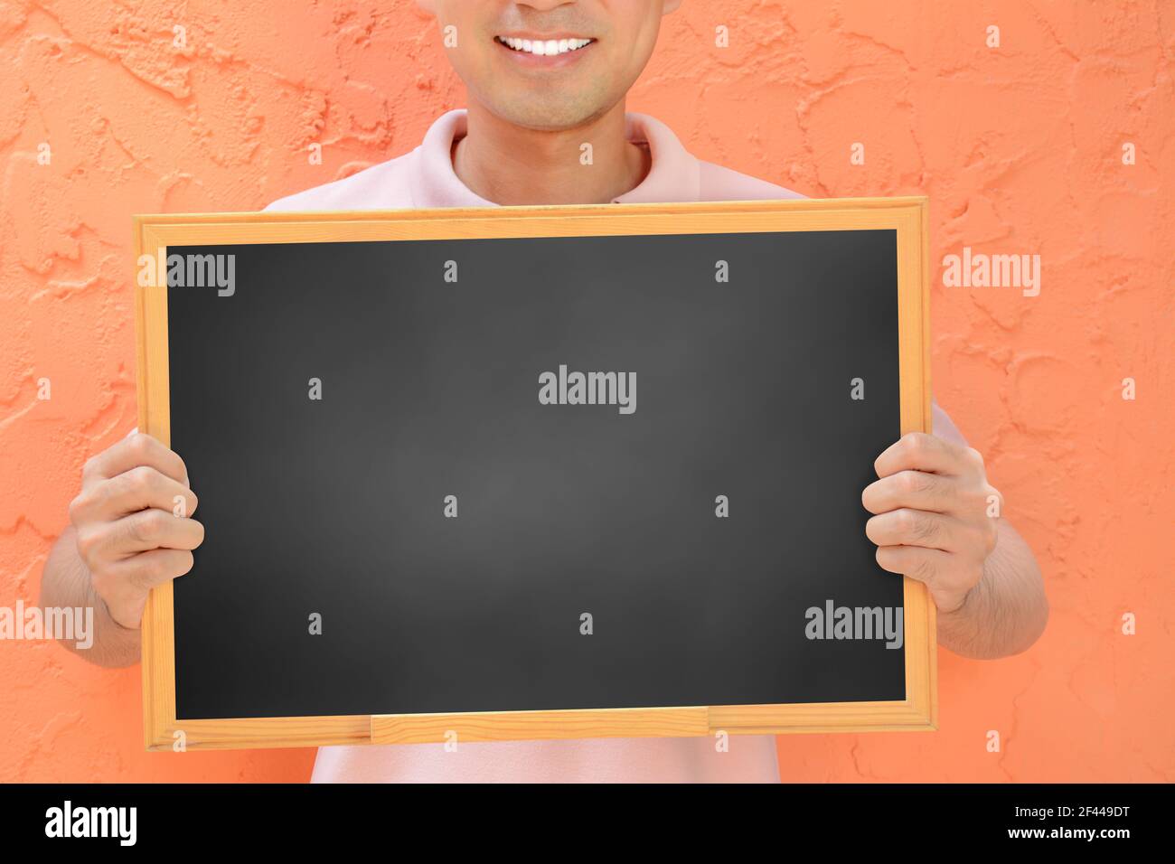 Homme souriant tenant un tableau noir vierge - peut remplir vos textes et être utilisé comme écriteau, avis et panneaux publicitaires, etc Banque D'Images