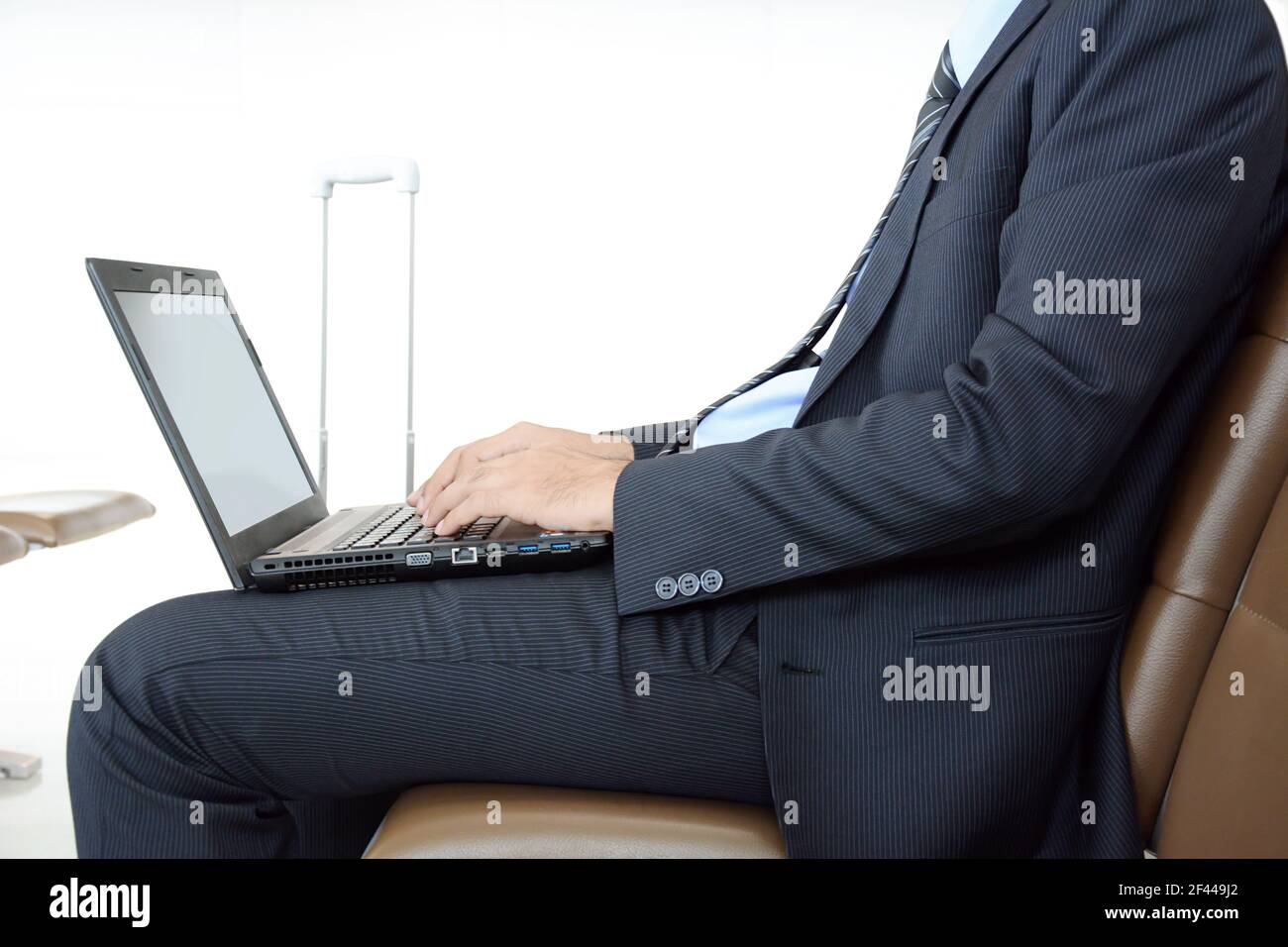 Homme d'affaires utilisant un ordinateur portable ou portable tout en étant assis sur le président à l'aéroport Banque D'Images