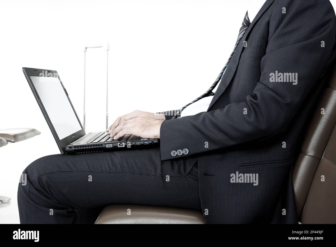Homme d'affaires utilisant un ordinateur portable ou portable tout en étant assis sur le président à l'aéroport Banque D'Images