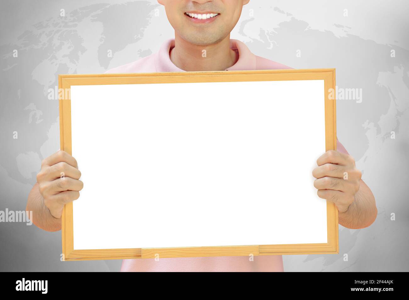 Tableau blanc vierge tenu par un homme souriant sur fond gris Banque D'Images