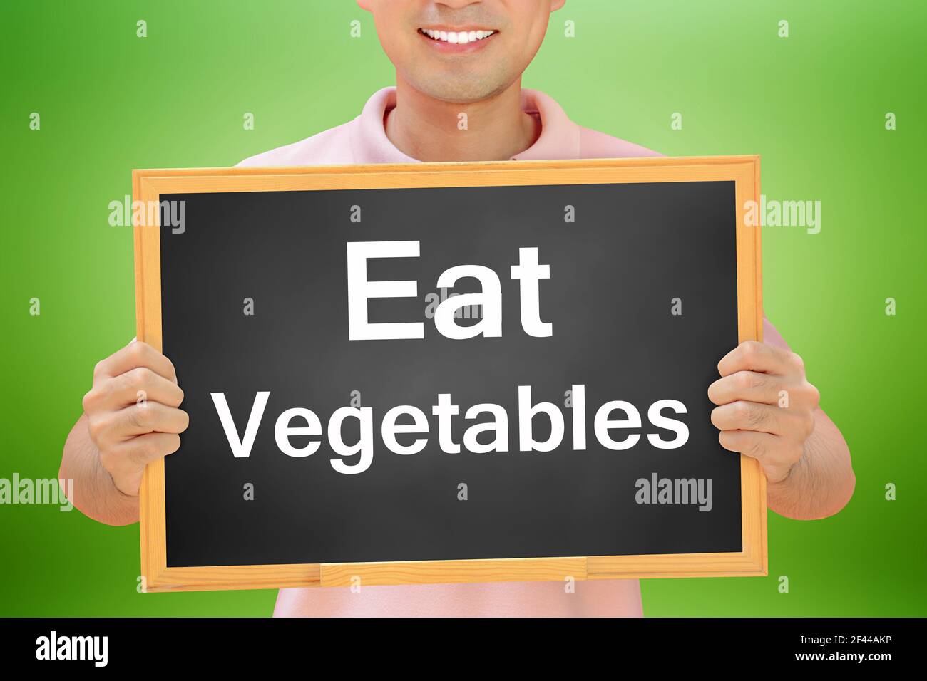 Mangez des mots de légumes sur le tableau noir tenu par l'homme souriant - concept de saine alimentation Banque D'Images