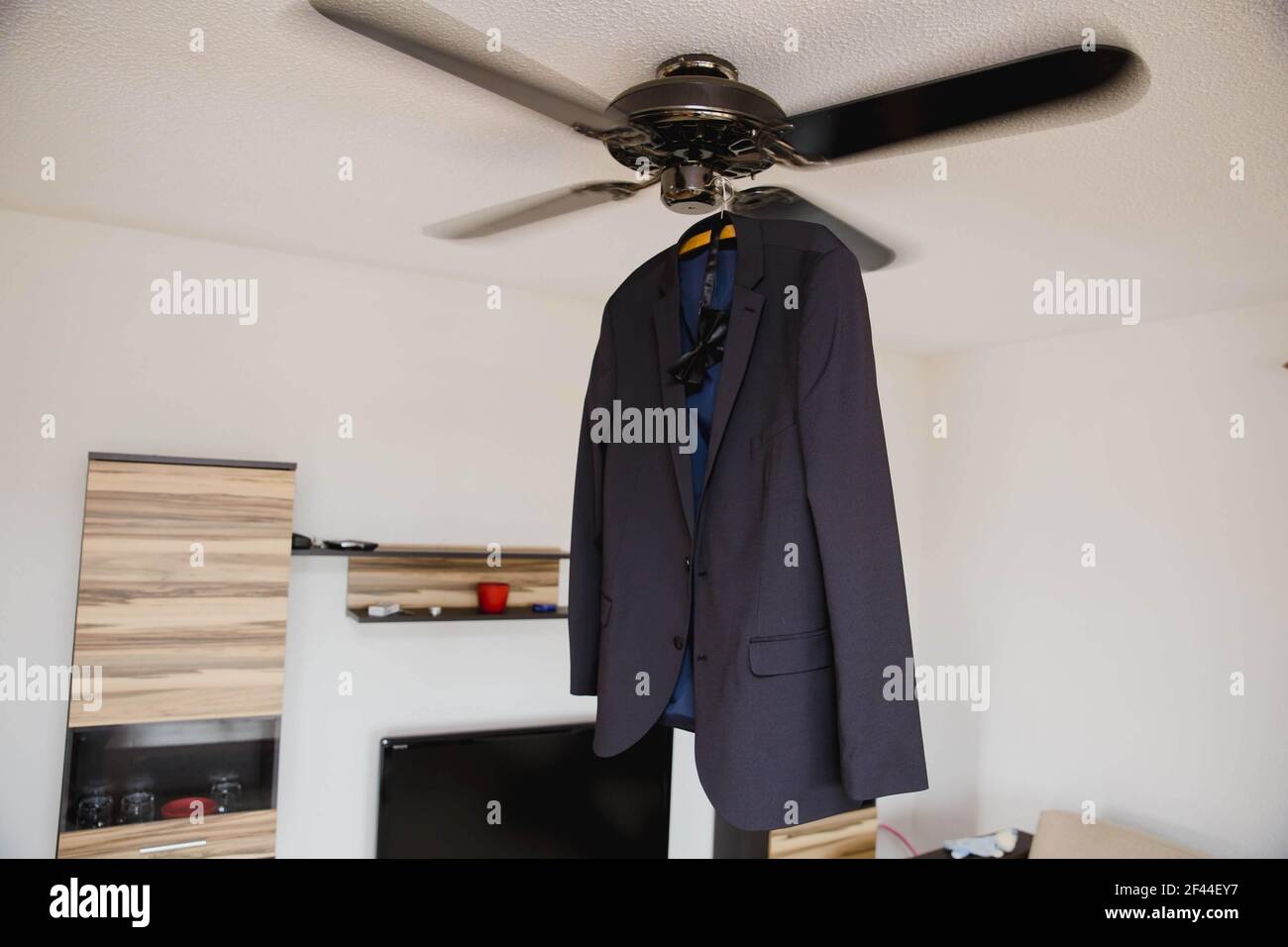 Un manteau et un noeud papillon accroché à un ventilateur de plafond Banque D'Images