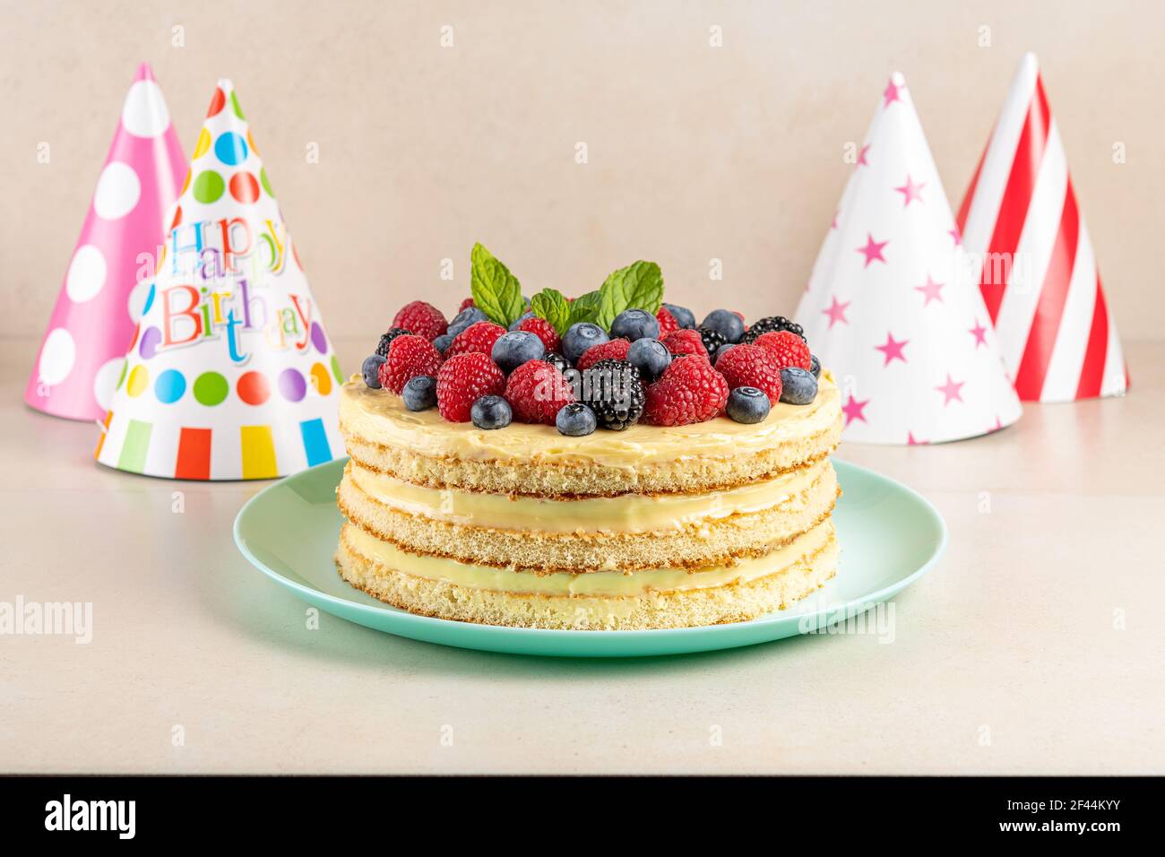Gâteau fait maison avec baies fraîches et chapeau d'anniversaire sur fond lumineux. Banque D'Images