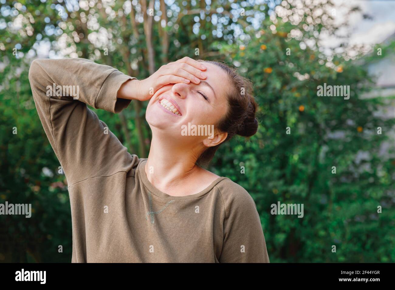 Jeune femme souriante à l'extérieur. Belle petite fille brunete reposant sur un parc ou un jardin vert. Femme heureuse gratuite en été. Liberté bonheur soins Banque D'Images