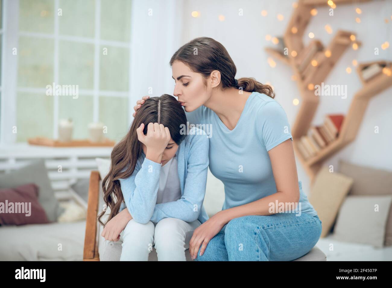 Maman aimante embrassant soigneusement sa fille bouleversée Banque D'Images