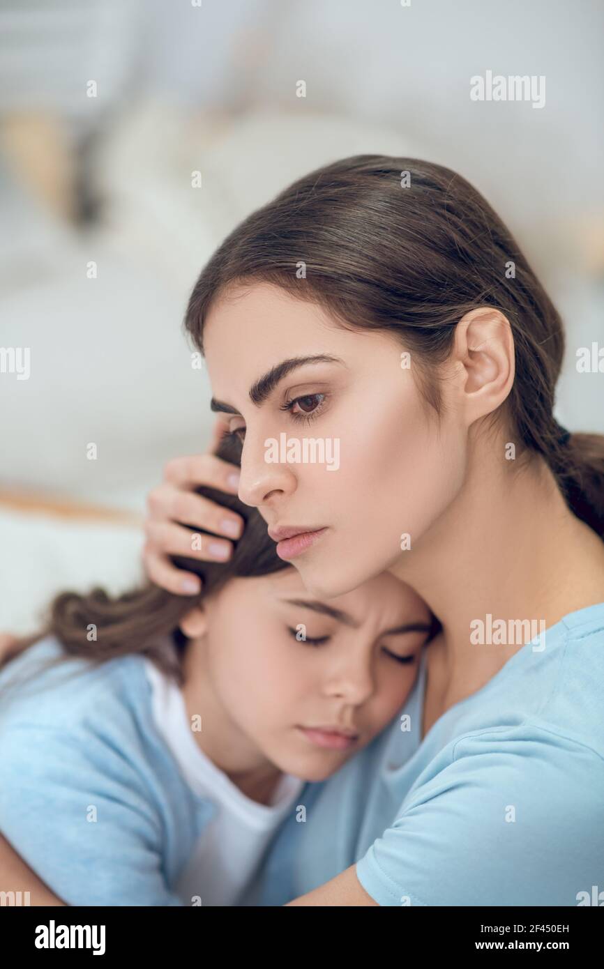 Maman embrassant la tête de la fille adolescente avec les yeux fermés Banque D'Images