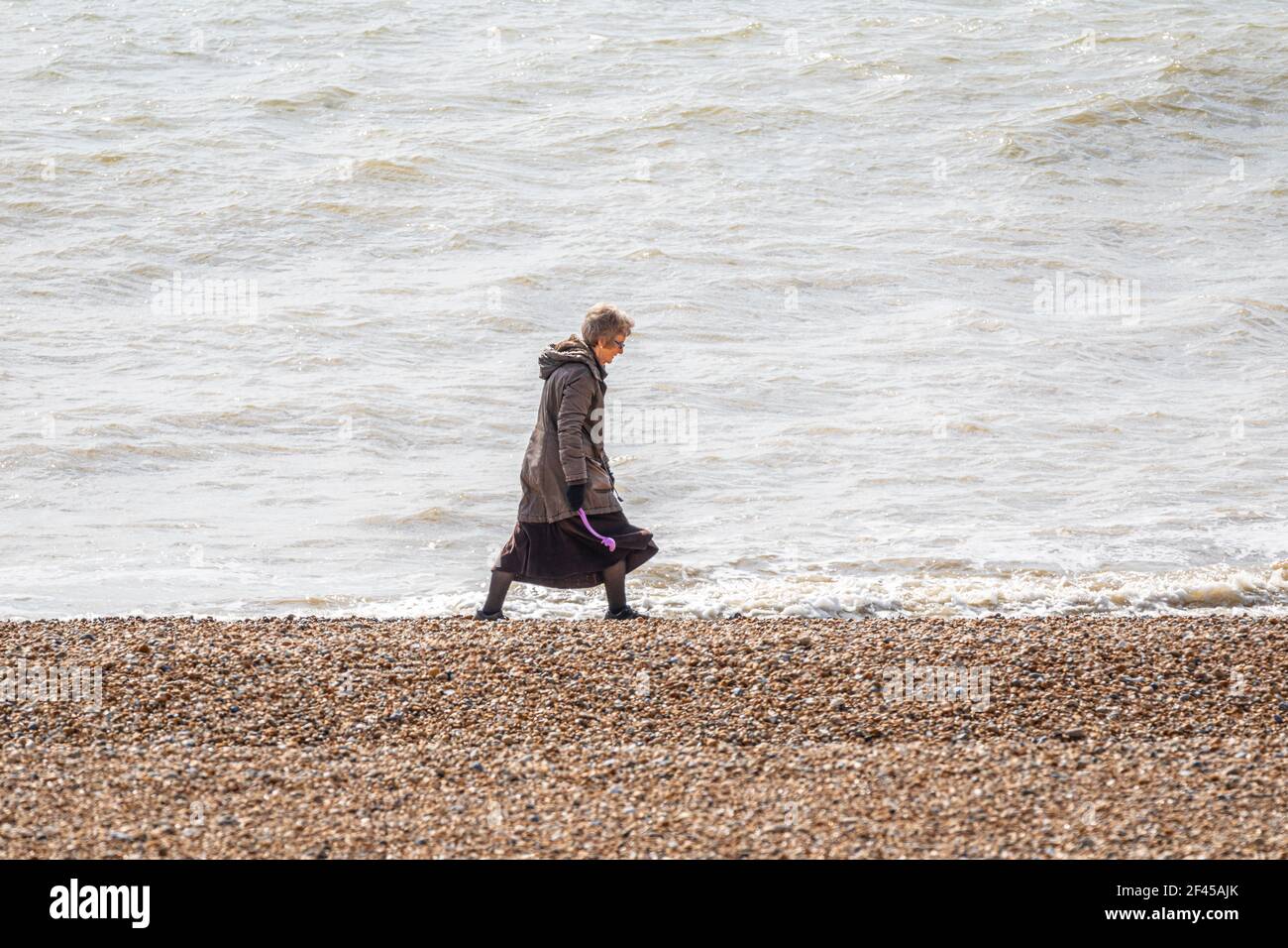 Un promeneur de chien solitaire près de la mer sur la plage d'Hythe, Kent. Banque D'Images