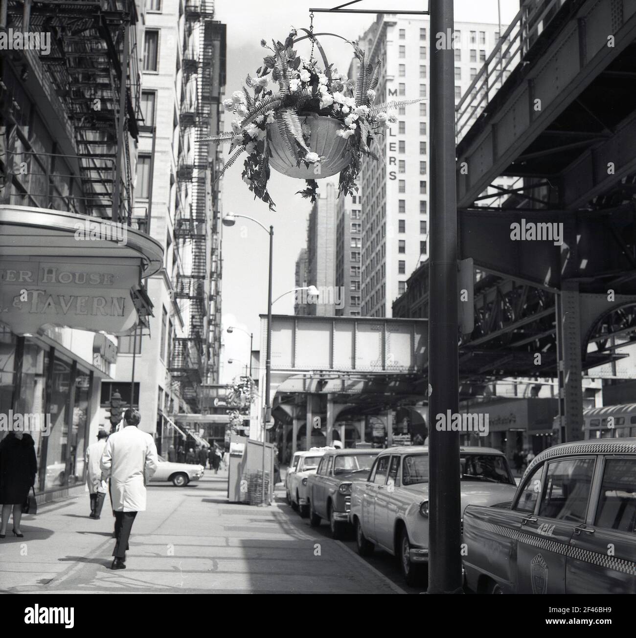1960s, historique, de jour et du centre-ville de Chicago, États-Unis, Wabash Avenue, montrant une section de la ligne de chemin de fer surterrestre ou surélevée, le Chicago 'l', le système de transport rapide desservant la ville, exploité par la Chicago Transit Authority (CTA). Voitures garées dans la rue, la taverne House sur la gauche et la tour Millers sur la droite. Banque D'Images
