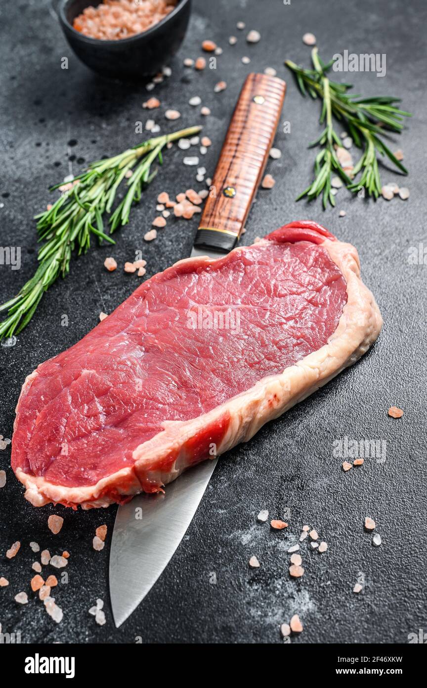 Striploin, strip loin steak ou New York. Bœuf cru. Arrière-plan noir. Vue de dessus Banque D'Images