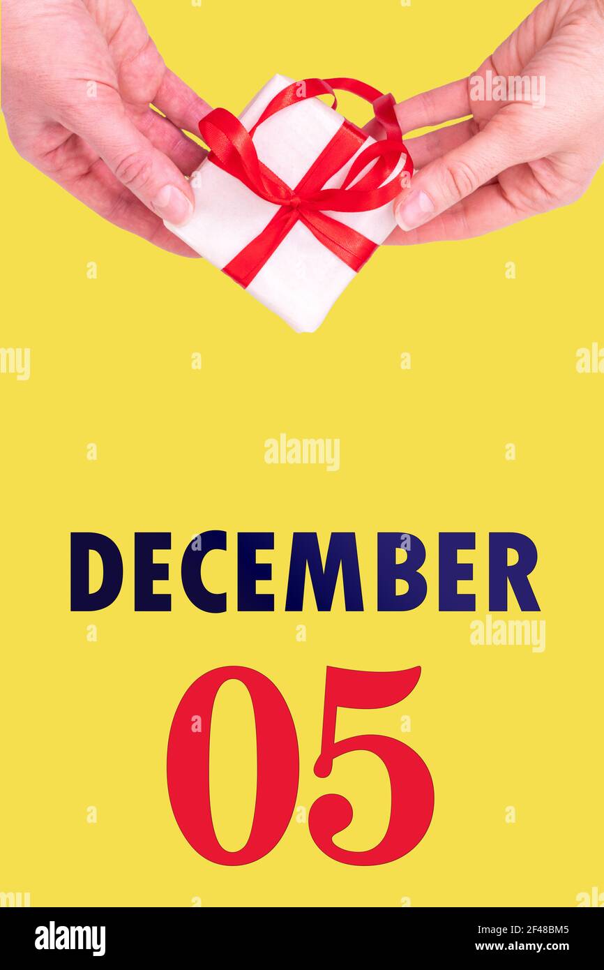 5 décembre. Calendrier vertical de fête avec mains tenant boîte cadeau blanche avec ruban rouge et calendrier Date 5 décembre sur fond jaune illuminant Photo Stock - Alamy